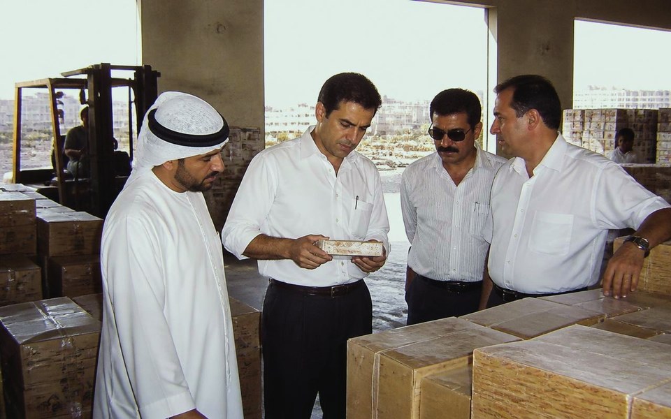2001, Port Rashid and the Deira trading quarter, Dubai, UAE: Warehouse staff and traders moving break-bulk cargo and shipping containers on the quayside at Port Rashid, Dubai, in 2001, with dhows and cranes behind them. — Avanti Holding, Avanti General Trading.