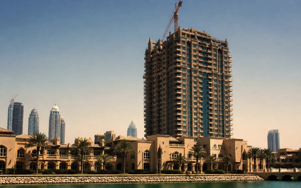 2004, Dubai, UAE: A post-tensioned concrete residential tower under construction against the Dubai skyline in 2004, with the site management team reviewing drawings on an upper floor. — Avanti Holding, Property Development.