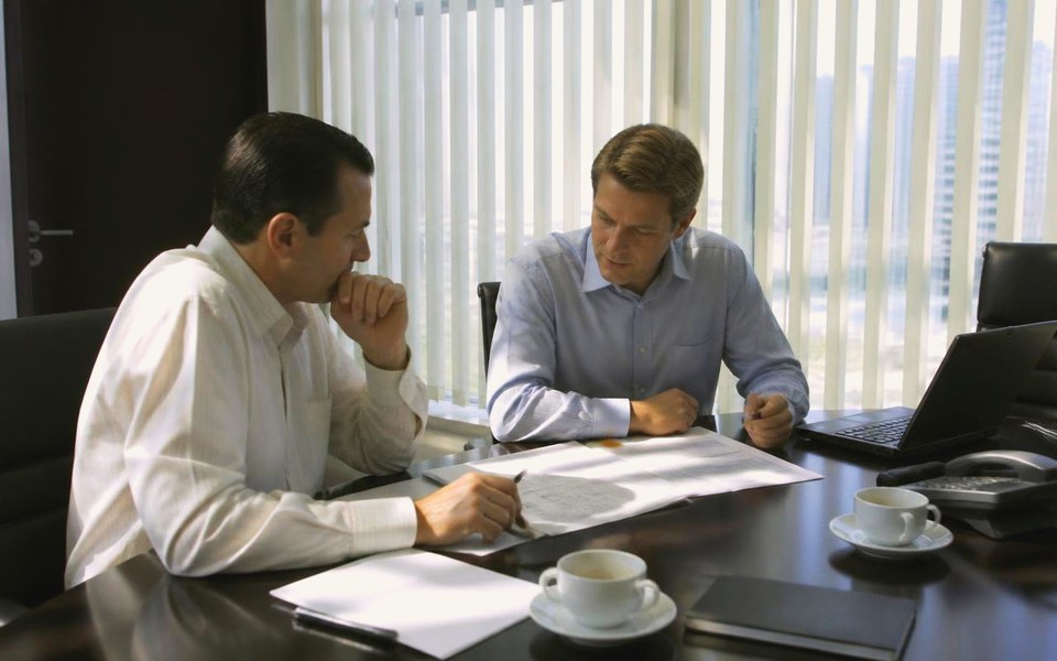 2008, Dubai, UAE, with the regional offices on the line: The chairman and finance team reviewing balance-sheet and cash-flow documents in a daylit Dubai meeting room during the 2008 restructuring. — Avanti Holding, Resilience.