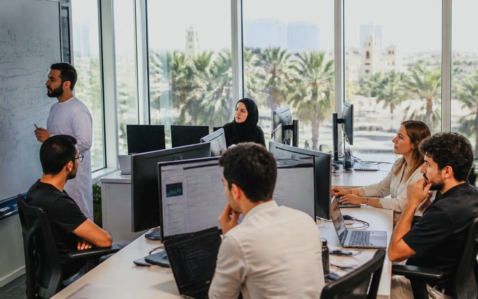 2021, Dubai Internet City, UAE: Research scientists at workstations in a Dubai AI lab reviewing computer-vision output and forecasting charts on large monitors in 2021. — Avanti Holding, Avanti AI Labs.