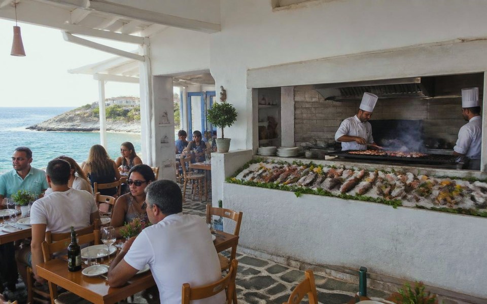 2027, Waterfront, Dubai, UAE: Visualisation of chefs working at the open kitchen, charcoal grill and iced raw bar of the planned Big Fish waterfront seafood house in Dubai, beside floor-to-ceiling windows onto the water. — Avanti Holding, The Big Fish.